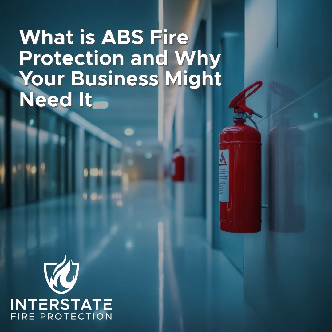 A sleek hallway with modern design and red fire extinguishers mounted on the walls, symbolizing fire protection. The title reads, "What is ABS Fire Protection and Why Your Business Might Need It," with the Interstate Fire Protection logo in the bottom left corner.